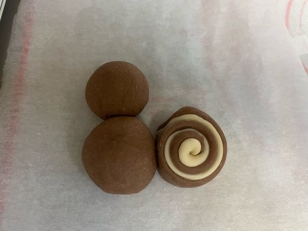 取60g巧克力麵團當頭，100g巧克力麵團當身體，切對半的雙色饅頭當尾巴，如圖示擺放