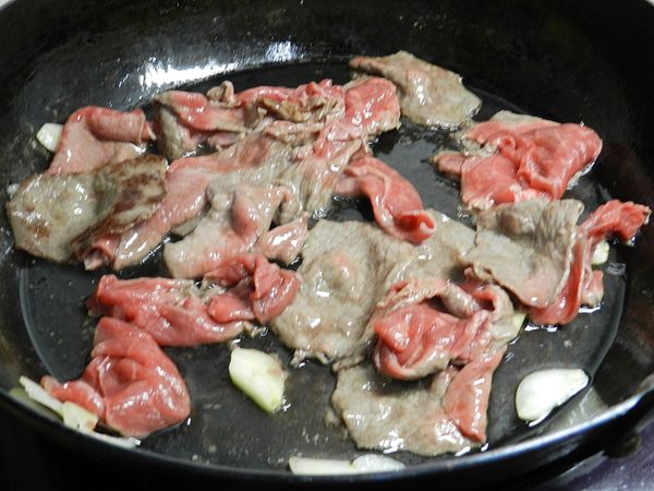 起一油鍋，炒香蒜片後下牛肉快炒