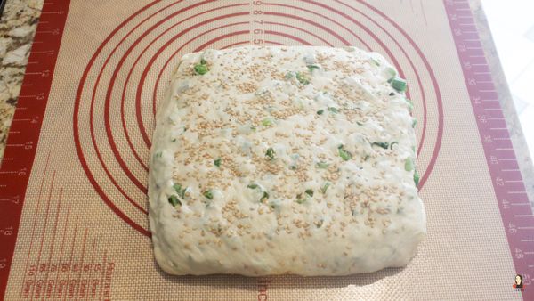 灑滿白芝麻、用擀麵棍擀一擀把芝麻壓進麵團裡