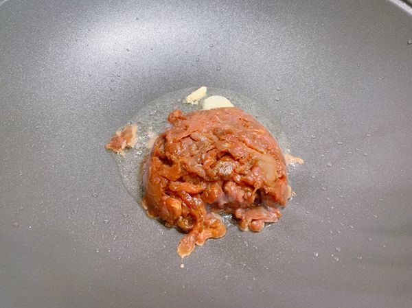 鍋內加入適量油，加入蒜瓣爆香後放入牛肉炒散。