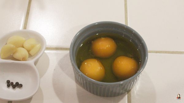 將橄欖油倒入放蛋黃的小碗中，加到可以完全蓋過蛋黃的分量。

小碗要選用可以進烤箱的，烤布蕾的圓形烤盅就很適合！尺寸也不要選太大的，才不用加很多橄欖油就能蓋過蛋黃。

不過也不用擔心會用掉很多橄欖油，油封後的橄欖油千萬不要丟掉！多了蒜頭與香料的風味，拿來做其他料理都非常好吃！