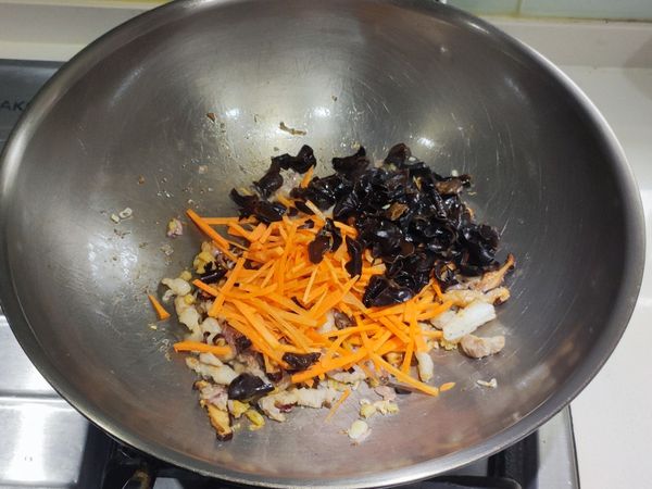 加入紅蘿蔔絲和木耳，炒至紅蘿蔔略軟化