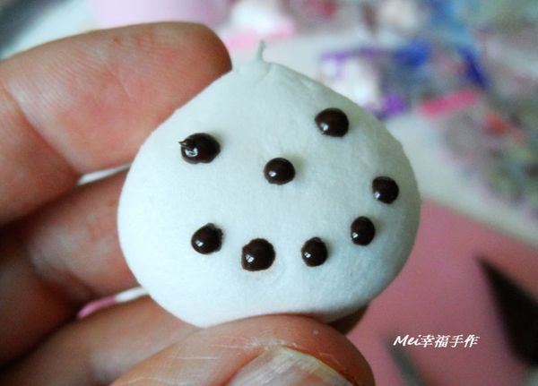 用融化的黑巧克力畫上眼睛和嘴巴，中間塗上少許黑巧克力，然後把草莓扁條軟糖放在中間黏住當成鼻子