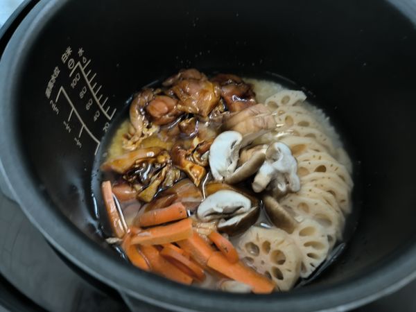 將紅蘿蔔粗條、醃好的雞腿肉、蓮藕片、切好的新鮮香菇片，平舖在米粒上。