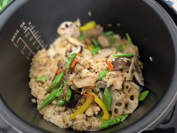 掀開飯鍋蓋，用五爪飯匙將燜好的米飯和配料輕輕撥動，讓受熱完全均勻，並讓多餘水氣排出。