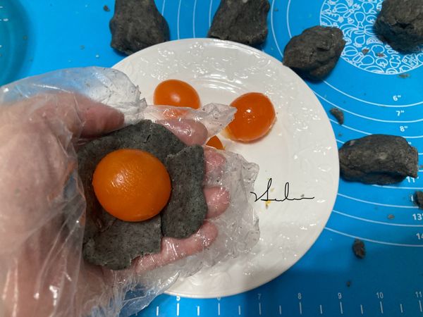 將巧克力麵糰壓成圖示，把蛋黃放入，包起來，雙手壓揉成圓。（圖為黑芝麻口味因為手機沒電）