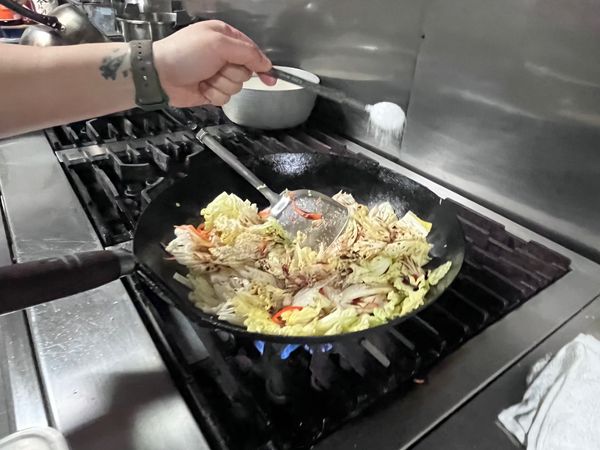 加入白菜，炒出水後開始調味，依序下入米酒、醬油、糖、鹽、香油，上色後