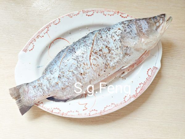 2.將鱸魚魚鱗刮除，去內臟、魚鰓，修剪魚鰭與魚尾，清理乾淨，魚身兩面可各劃2斜刀，以[醃料]醃漬1小時(期間將其翻面一次)。