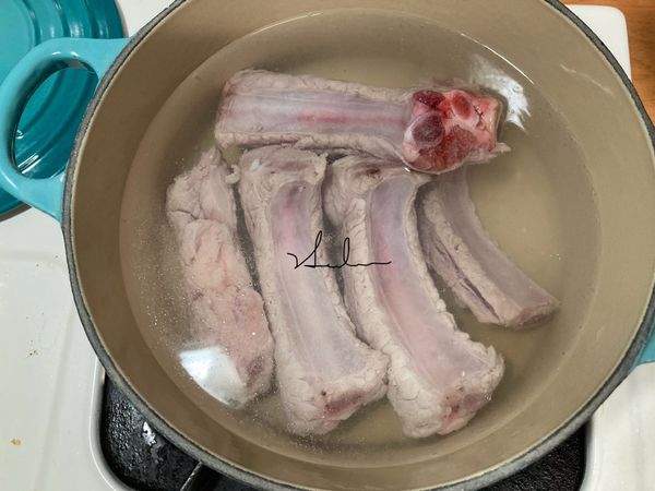 將豬肋排連水需蓋過肉在鍋內加入米酒煮8分鐘，主要的目的是要把血水和髒髒的東西清掉。我使用的是18公分鑄鐵鍋，可以使用一般的鍋子煮（不ㄧ定使用豬肋，也可以選肉多些的排骨）