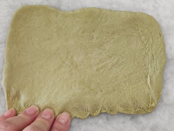 用手指將下方的麵糰邊邊由上往下按壓薄