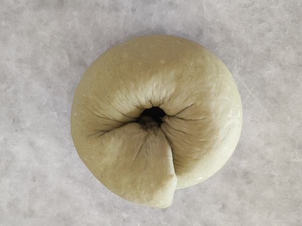 麵糰的另一頭略微搓細，然後放在擀寬的麵皮上環成圓形，再用擀寬的部份包住，捏緊收口。