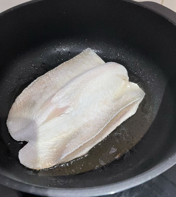 將鹽均勻抹在虱目魚肚上。熱油鍋，鍋熱後，將魚肚朝下，放入鍋中，煎5分鐘。