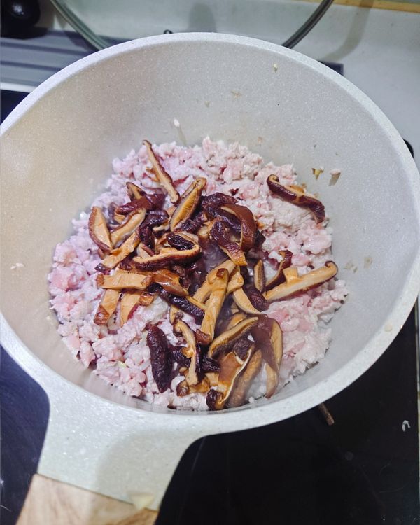 絞肉炒到變白後加入香菇絲，加入米酒煮到滾（提升豬肉甜味和去腥）