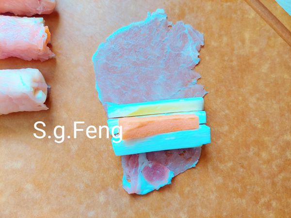 3.將筊白筍與紅蘿蔔等分為12等份，取一片肉片，將1等份的筊白筍與紅蘿蔔橫放在肉片前端。