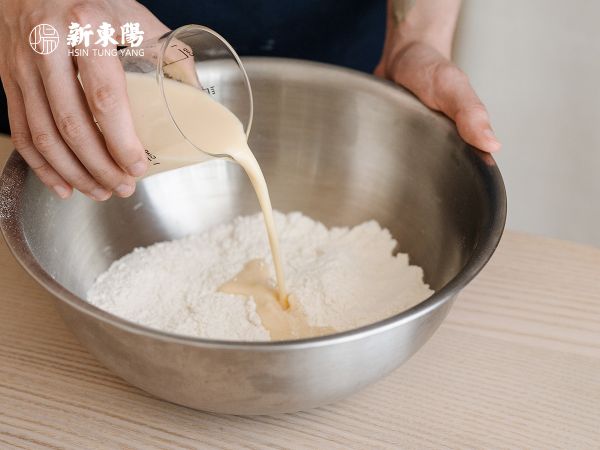 將中筋麵粉、泡打粉、小蘇打和鹽混合均勻後，將雞蛋和常溫豆漿拌勻，再分3至4次拌入。
