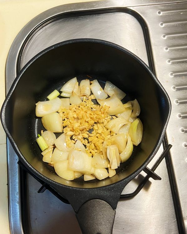 鍋中放入香油，以中小火炒香洋蔥、大蒜與蔥白。