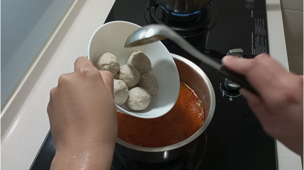 鍋中加入500ml的水及叻沙醬，開中火煮滾後放入虱目魚丸先煮5分鐘。