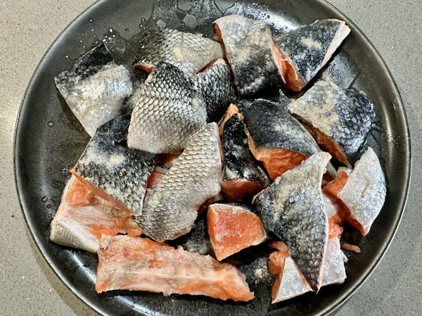●買六片後切輪切鮭魚老闆送鮭魚尾段，烹煮前沖洗過用料理剪刀剪3公分塊狀，在皮面灑上鹽跟白胡椒各1/4小匙（不在材料裡）。如不趕時間煮，冷藏乾淨空曠可放冷藏，讓冰箱把魚上面的水吸乾，這樣就可不用廚房紙巾再拭乾魚肉上的水，少用兩張廚房紙巾多點環保，如果冷藏很飽滿沒空間或急著煮直接用廚房紙巾拭乾防油爆。