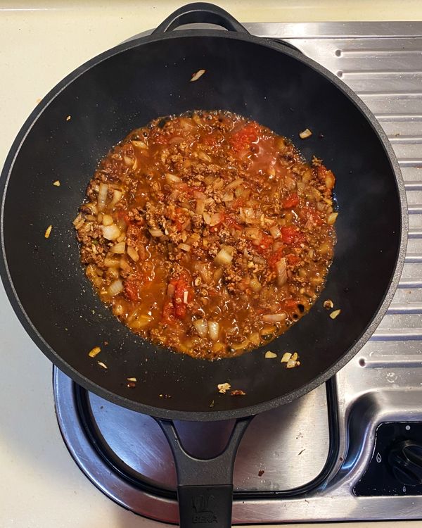 加入紅酒、番茄罐頭與義式綜合香料。
待醬汁滾沸後，再燒煮約3分鐘。