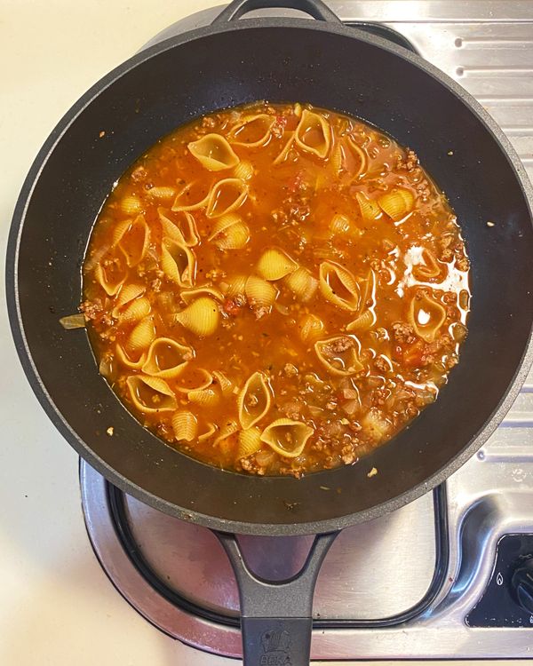 加入清水與貝殼麵，轉小火，烹煮約10分鐘至麵熟透。