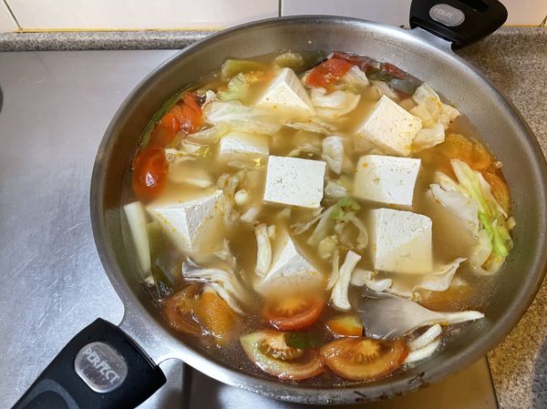 放入另一半蕃茄、高麗菜、菇類、豆腐，煮約10分鐘