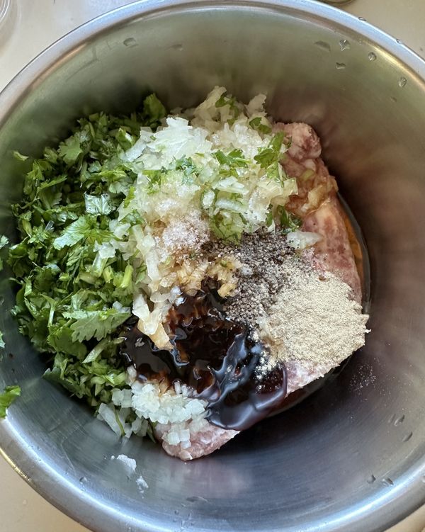 將豬絞肉、洋蔥末、及調味料（鹽、胡椒粉等）全部放入大碗中，並加入大量切碎的香菜。