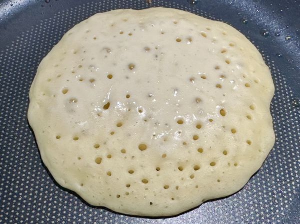 ●平底鍋加酪梨油1/2小匙（不在材料裡）搖晃一下潤鍋，用大湯匙挖進麵糊，從鍋中心慢慢倒下麵糊喔，這樣才會是圓形，設定計時器蓋上鍋蓋悶煎2分鐘，表面有洞洞代表熟了可以翻面。