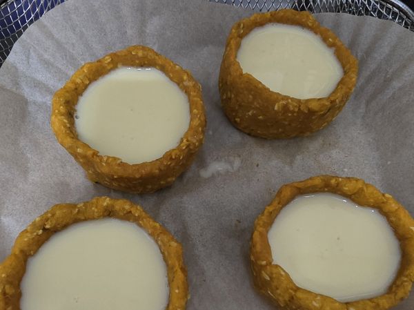 攪拌好的蛋塔液倒入烤好放涼的蛋塔皮中，倒入約9分滿。