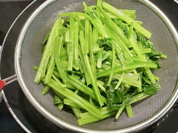 ●把燙熟的菠菜夾到撈麵勺裡。
