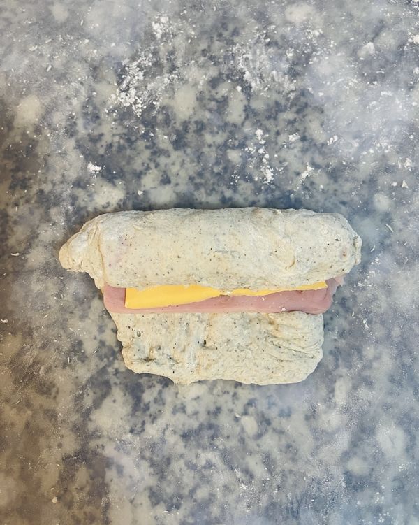 捲起來，用麵糰兩邊包覆兩頭的起司火腿；