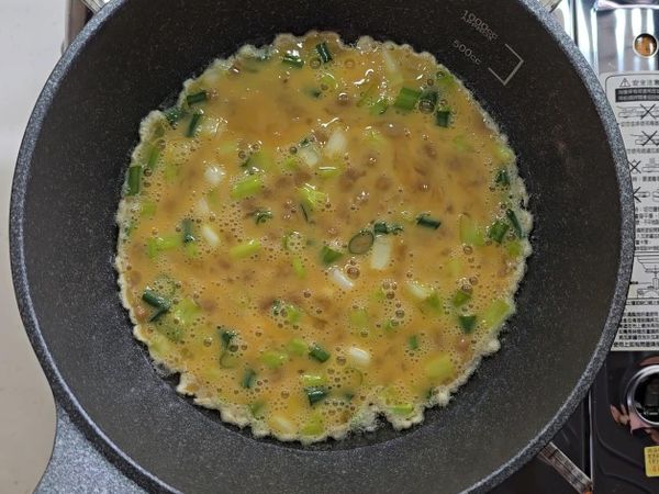 先加入适量的油然后开中小火,再把攪拌好的蛋液倒入鍋中。這時候在鍋中把納豆攤開。