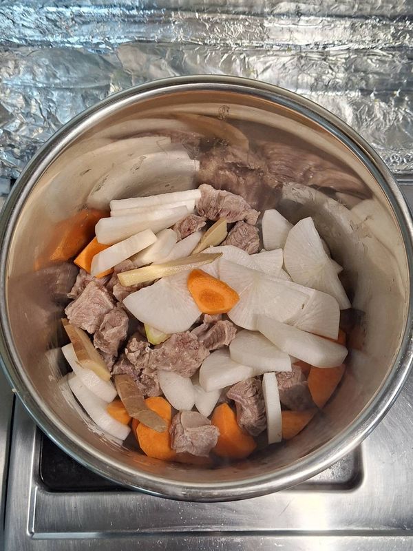 老薑切片、青蔥打結，白蘿蔔切薄片、胡蘿蔔切滾刀塊，所有食材加入鍋中