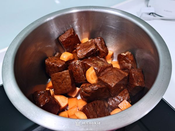 放入紅蘿丁及豆干稍為乾煎（需小火），倒入清醬油及醬油膏稍拌抄出食材香氣