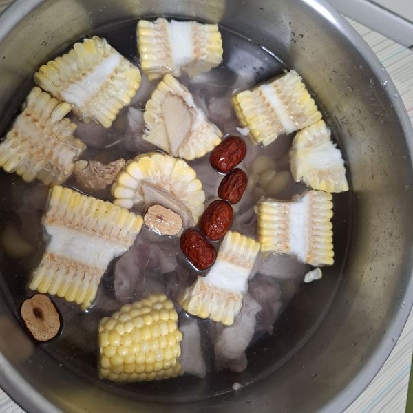 將排骨 紅棗，薑片，玉米段，蒜仁與米酒放入電鍋內鍋，加水淹過食材。