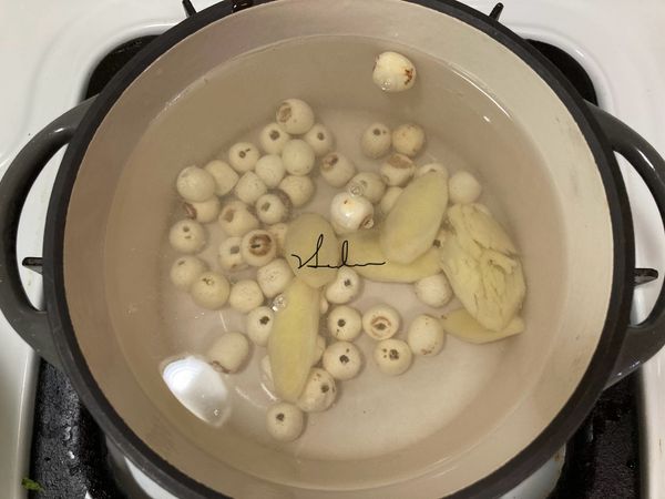 將鍋內放入500ml/cc的水(我的小鍋可以放入總水量700ml)，同時放入蓮子與薑片，小火，蓋上鍋蓋，不可以全蓋，要留一些些縫隙，否則水滾時它會噗鍋。設定計時器10分鐘。(也可以使用電鍋操作)