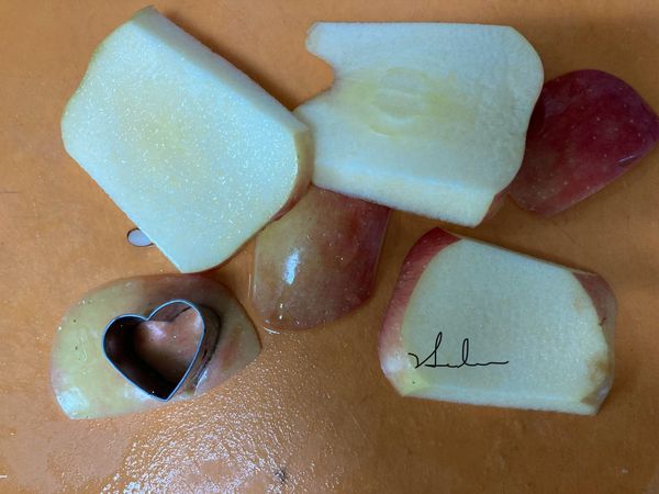 在煮蓮子的時侯，來處理華盛頓聖芳蘋果，先切成約圖中樣子，不要太薄也不要太厚。要用模子壓花，所以切成片的時侯要注意模子的面積、避開中間的芯，才可以作出較多的數量。泡入鹽水中。有皮的部分要壓6個來配色。總共18鍋內+6配色共需24個。