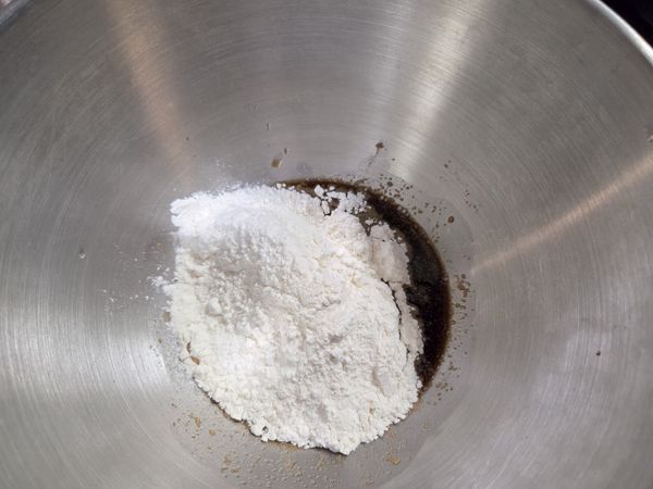 盆中酵母粉與黑糖水稍微拌勻，倒入麵粉與鹽攪拌搓揉至無粉