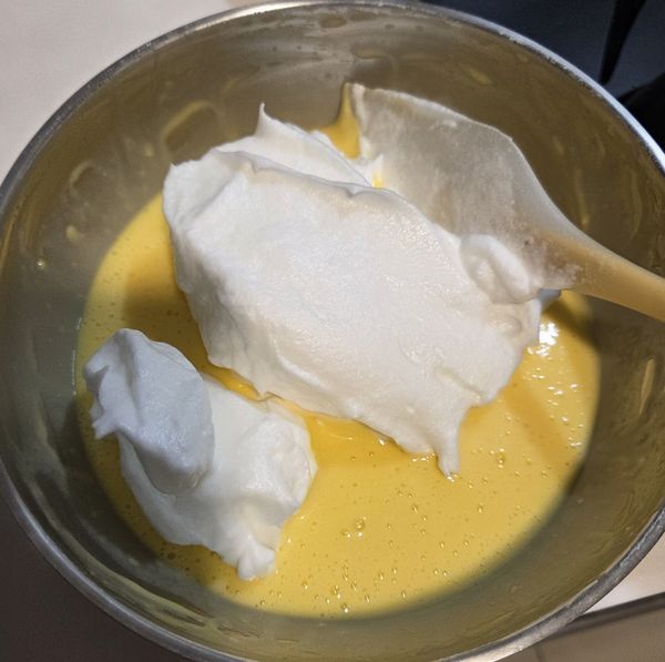 取1/3蛋白霜到蛋黃糊裡，用刮刀輕輕翻拌均勻 
→ 再全倒回剩餘蛋白霜 → 2 次翻拌均勻（動作快但輕，消泡少）。