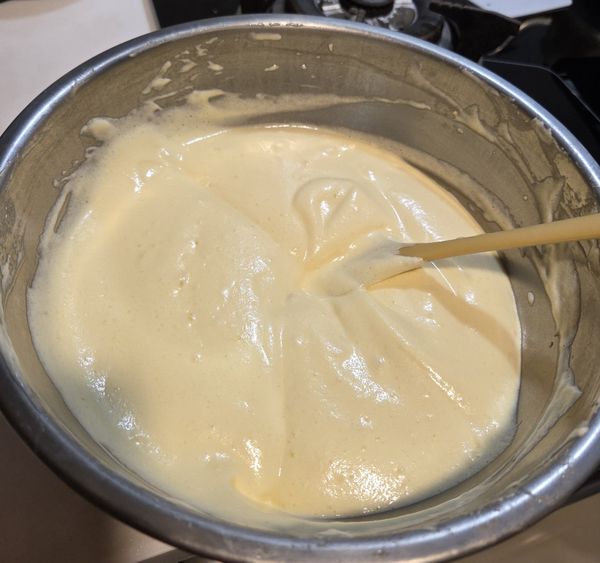 拉高垂直倒入烤盤，
用刮板由中間往四周推平，輕敲烤盤排大氣泡。