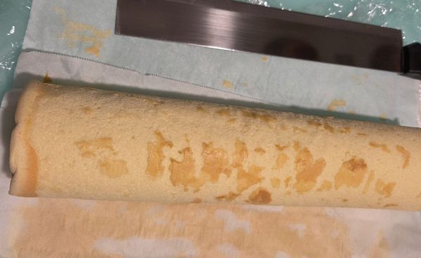 貼近烤盤的那一面塗抹藍莓醬，這次塗的很薄，下次要塗厚一點味道會更好，30公分那一面朝向自己，用桿麵棍貼著烘焙紙，先向內向下壓，慢慢的捲動烘焙紙，即可捲起。
（這次的烘焙紙沒有刷油，所以皮都黏在烘焙紙上了。）