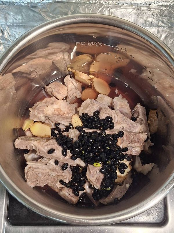加入薑片、米酒、黑豆（連同泡黑豆水）、清水