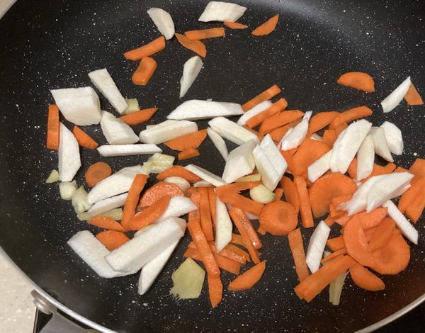 筊白筍去粗纖維後切細放入後炒，接著切胡蘿蔔與華盛頓富士蘋果，與筊白筍一同放入翻炒