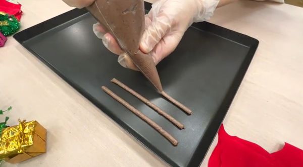 裝入擠花袋，在鋪好烘焙紙的烤盤上，擠出約 10–12 公分長條。