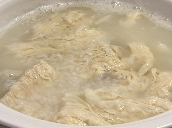 加生豆皮，再煮25分鐘。豆皮容易黏鍋底，所以記得不時攪拌。生豆皮會慢慢化開，最後溶在粥裡面。