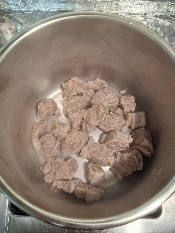 焯好的牛肉放入壓力鍋，加入蔥、薑、米酒、燉肉料包、清水