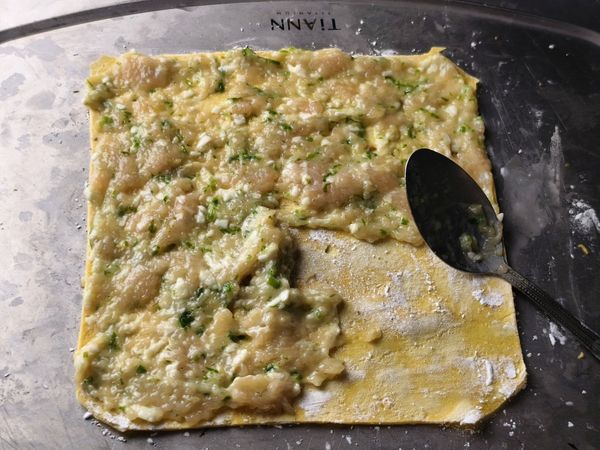 雞肉漿分成兩等份，一份鋪平在蛋皮上，用較大的湯匙鋪平。有保鮮膜的話，蓋到雞肉漿上面，用桿麵棍鋪平，這也是好方法。