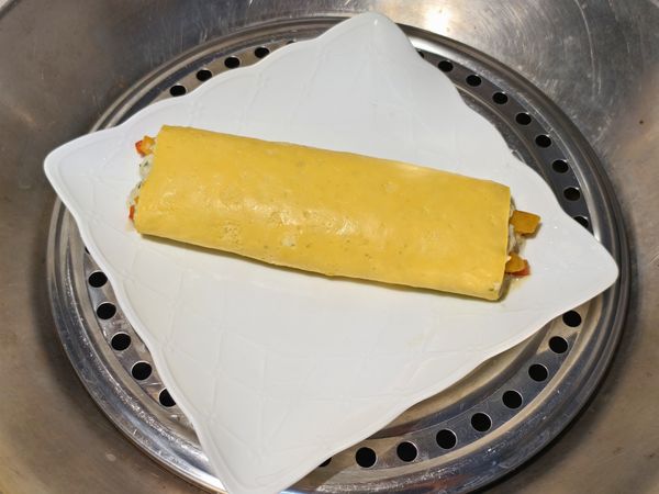 慢慢翻面，黏合處要朝下，稍微整形。盤子上一定要抹些油，再把如意雞肉捲移到盤子上面。鍋子水滾了之後，中火蒸8到10分鍾。蒸兩條就10到12分左右。