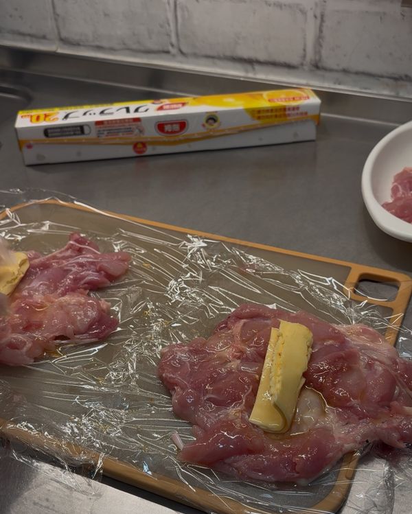 捲製與固定
1.鋪好保鮮膜，雞肉皮朝下放好。
2.依序鋪上起司片（起司片可對摺放在中央防止溢出）。
3.緊密捲起：因為厚度已處理均勻，請順勢拉緊保鮮膜，將肉捲成圓柱狀。