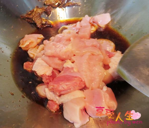 將雞腿肉放入麻油鍋中炸至變色，再加入一瓶蓋的醬油，讓雞肉上色。