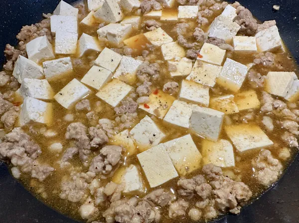 ●把豆腐生出的水倒掉，將（豆腐塊）倒進鍋中，用炒匙輕推讓豆腐都沾到醬汁，前後搖晃鍋子讓豆腐淹沒在醬汁中，小火蓋鍋燒煮3分鐘。